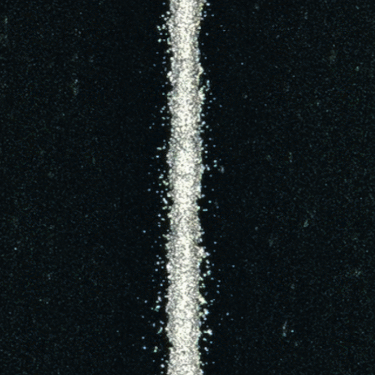 A silver line of fire through paste. A top view of a silver line that has been screen printed onto a black background.